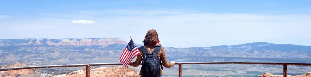 Tourist looking out over National Park while having an American flag in her backpack